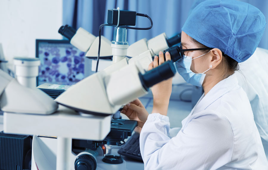 Technician analyzing a sample under microscope